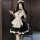 A woman poses in a black and white maid costume with ruffles, holding a phone. the outfit features a collar and apron design,...