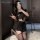 A woman poses with a smartphone, wearing a black schoolgirl-style pleated mini skirt paired with stockings. the outfit featur...
