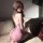 A woman sits on a couch wearing a sheer pink xishi sexy kimono sleep dress, featuring a back tie design, creating an elegant ...