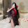 A woman poses on a bed wearing a sheer black hanfu-inspired erotic robe with red accents, capturing an intimate moment. the d...