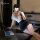 Woman in yaqin nu lingerie set with lace top and bodycon skirt, posing by desk with laptop for elegant date night look.