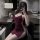Woman in yaqin nu burgundy sleep dress with low-cut neckline and high slit, taking mirror selfie in lounge setting.