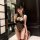 Woman wearing black lace yaqin nu open-crotch nightgown with hook-neck detail, posing in elegant bedroom setting for date nig...