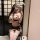 Woman in yaqin nu sexy lingerie set with striped mini skirt, matching top, lace thigh-highs, and bunny ears mask.