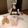 A woman wearing a yasu cosplay maid costume, featuring a cute anime-style sexy sleepwear and roleplay uniform, sitting on a b...
