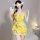 A woman poses with a phone, wearing a yellow floral lace bodysuit set. the outfit features spaghetti straps and a tie-front d...