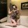 Woman in yeqin nu lingerie set, vintage sheer cheongsam with high slit, holding fan on sofa.