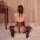 Woman wearing yeqingge sheer bodysuit with open-crotch design, seated on bed in elegant lingerie set.