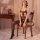 Woman wearing yeqingge sheer bodysuit with open-crotch design, seated on wooden chair in elegant lingerie set.