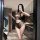 Woman modeling yese yese lace trim mesh bodysuit set with sheer floral cut-out bra and panty in modern kitchen.