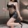 A woman poses elegantly in a black lace bodysuit, featuring an open-crotch design, holding a glass of wine while wearing high...