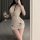 A woman poses with a glass of wine, wearing a sheer lace cami and bodycon nightdress set. the elegant design features intrica...