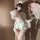 A woman poses with a pink parasol, wearing a delicate white kimono-style outfit paired with bunny ears and floral accessories...