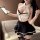A woman models a stylish black and white lingerie set, featuring a halter top with lace detailing and a flared skirt, perfect...