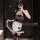 A woman poses in a black and white maid costume set, featuring sheer mesh lingerie with bells, perfect for cosplay or adult e...