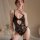 Woman modeling yue die black lace bodysuit with sheer panels and open-crotch design, elegant sleepwear for seductive allure.