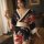A woman wears a black floral japanese-style robe set, featuring vibrant red flowers and beige accents, perfect for couples sl...