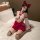 Woman modeling zhongqu sexy chinese-style lingerie set with sheer top, red bow skirt, and thigh-high stockings on bed.