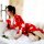 A woman lounges on a bed wearing a red japanese-style lace robe with floral patterns, featuring a deep v-neck and long kimono...