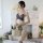 A woman models a sexy sheer lace top paired with a beige satin skirt, holding a wicker basket of flowers. the set features el...